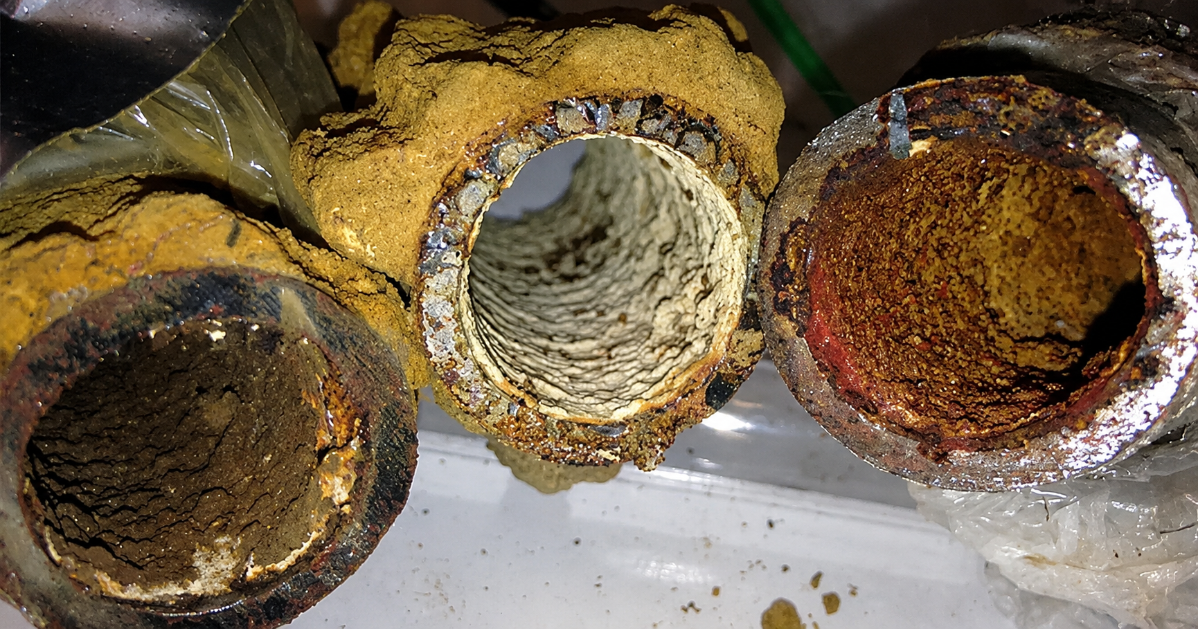Corroded water pipes showing rust and mineral buildup inside